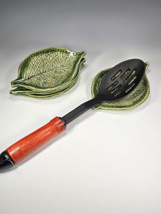 two green leaf shaped dishes and a red spatula