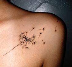 a woman's shoulder with a dandelion tattoo on it