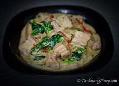 a black bowl filled with meat and vegetables on top of a dark countertop,