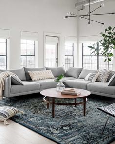 a living room filled with lots of furniture next to two windows and a rug on the floor