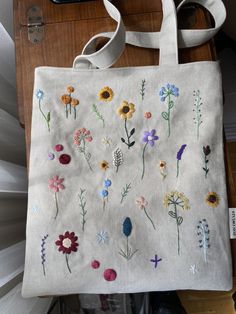 a bag with embroidered flowers on it sitting on a table next to a cell phone