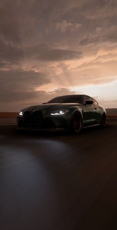 a green sports car driving down the road at night with dark clouds in the background