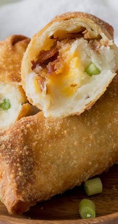 an egg roll on a wooden plate with some green onions and other food items around it