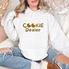 Introducing our Funny Cookie Dealer Hooded Sweatshirt, the perfect blend of comfort, style, and humour. Whether you're lounging at home, running errands, or hanging out with friends, this sweatshirt will keep you cozy and get some laughs along the way. Features: Premium Quality: Made from a soft and durable cotton-polyester fabric, this sweatshirt offers a cozy fit that's perfect for any season. Custom Graphic: The custom Nurse & Name design is printed with high-quality, fade-resistant ink, ensu Casual Cotton Christmas Hoodie, Casual Christmas Cotton Hoodie, Christmas Long Sleeve Cotton Hoodie, White Cozy Fit Hoodie With Crew Neck, Christmas Cotton Hoodie With Letter Print, Cropped Tshirts, Cotton Polyester Fabric, Custom Sweatshirts, Sweatshirt Christmas