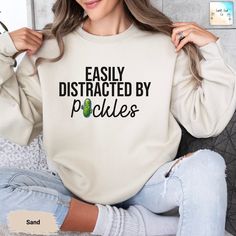 Stay cozy and showcase your quirky side with our "Easily Distracted by Pickles" sweatshirt. Featuring a fun pickle graphic, this soft and comfortable sweatshirt is perfect for casual wear or lounging at home. Embrace your love for pickles and add a touch of humor to your wardrobe. --- How To Order ----- 1-) Please, check and review all the photos. 2-) Choose your sweatshirt size and color. 3-) Click add to cart. You can go back to add more sweatshirts. 4-)Click "Proceed to check out". 5-)When yo Cute Slogan Sweatshirt Relaxed Fit, Relaxed Fit Crew Neck Sweatshirt With Funny Print, Relaxed Fit Sweatshirt With Funny Print For Loungewear, Funny Crew Neck Sweatshirt With Relaxed Fit, Funny Slogan Sweatshirt In Relaxed Fit, Funny Text Relaxed Fit Sweatshirt, Funny Relaxed Fit Crew Neck Sweatshirt, Relaxed Fit Crew Neck Sweatshirt With Funny Text, Pickle Graphic