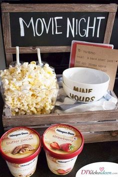 two cups of ice cream next to a bowl of popcorn and a sign that says movie night