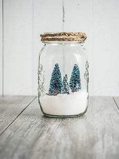 a glass jar filled with snow and trees