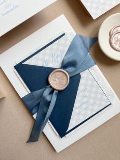 a wax stamp on top of a blue and white wedding card with a ribbon tied around it