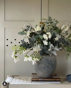 a vase filled with white flowers sitting on top of a table next to a stack of books