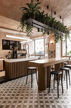 the interior of a restaurant with potted plants hanging from the ceiling and bar stools