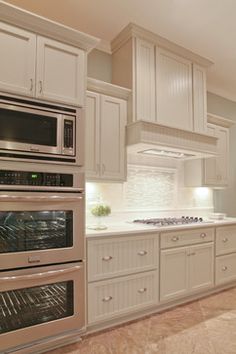 a large kitchen with white cabinets and stainless steel appliances, including an oven, microwave, dishwasher