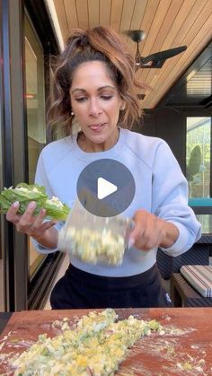 a woman is cutting broccoli with a knife on a wooden table in front of her