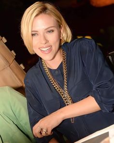 a woman sitting at a table with a laptop computer in front of her and smiling