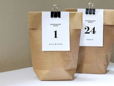 two brown paper bags sitting on top of a table with numbered tags attached to them