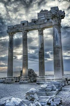 the ruins of an ancient city are shown against a cloudy sky with sun peeking through