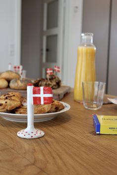 a wooden table topped with plates of cookies and orange juice