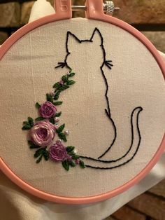 a hand embroidered cat with flowers on it