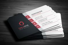 four business cards stacked on top of each other in front of a wooden table with black and red accents