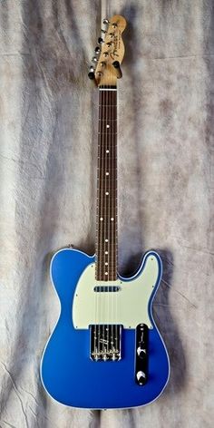 a blue and white guitar sitting on top of a bed