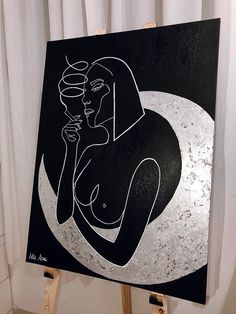 a black and white painting sitting on top of a easel