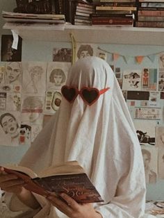 a person in a white robe and heart shaped glasses reading a book on a bed