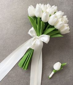 a bouquet of white tulips tied to a ribbon with a flower on the side