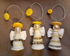 three necklaces with yellow buttons and white bows are hanging on a brown tablecloth