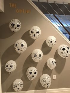 there are many balls with faces on them in the shape of skulls hanging from the wall