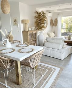 a living room filled with furniture and a white dining table surrounded by wicker chairs