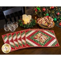 a table topped with plates and cups filled with christmas treats next to a lit candle