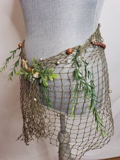 a mannequin is adorned with plants and beads