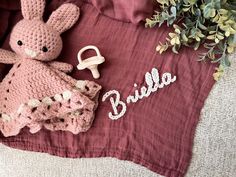 a pink crocheted bunny is laying on a blanket next to a flower pot