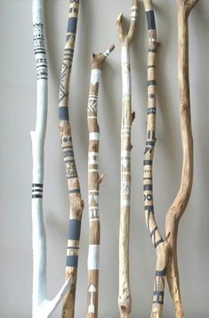 several different types of wooden sticks hanging on a wall with writing written on them and some are made out of driftwood