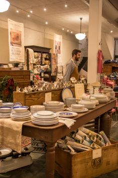 a man standing in front of a table filled with plates and bowls on top of wooden boxes