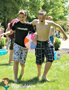 two young boys are standing in the grass holding frisbees and smiling at the camera