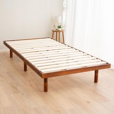 a bed frame sitting on top of a hard wood floor next to a white wall