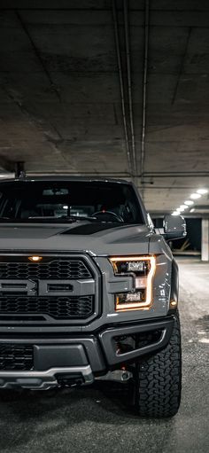 a truck parked in a parking garage with its lights on and it's hood up