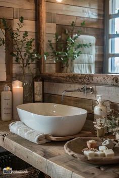 a white bowl sink sitting on top of a wooden counter next to candles and flowers