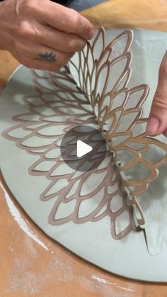 a person is making a paper flower on a glass plate with scissors and glue to it