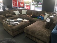 a man laying on top of a brown couch in a room with lots of furniture