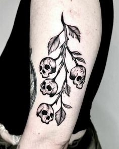 a woman's arm with skulls and leaves on it