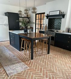 a kitchen with an island table and stools in the center, surrounded by black cabinets