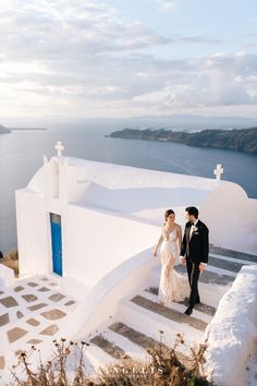 a bride and groom walking up the stairs to their wedding ceremony in oia, greece