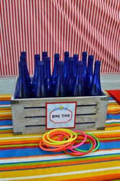 there are many blue bottles on the table with rubber bands around them and one has a ring toss in front of it