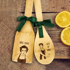 two wooden spoons with pictures on them next to slices of lemon and an orange