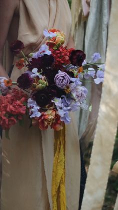 a bride holding a bouquet of flowers in her hand with other people standing behind her