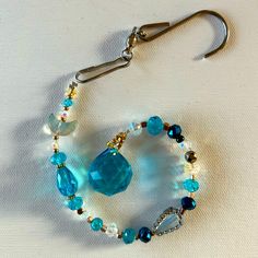 a pair of blue and white beaded bracelets hanging from hooks on a white surface