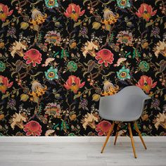 a chair sitting in front of a black wallpaper with colorful flowers and leaves on it