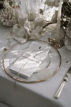 the table is set with white flowers and silverware