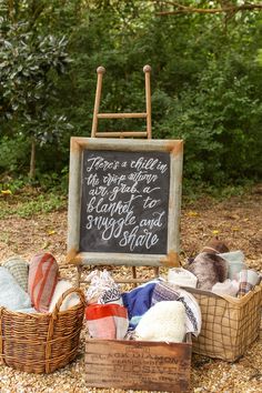 a sign that is sitting on the ground with some clothes in baskets next to it